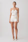 Woman wearing a white strapless top and shorts with gold hardware.
