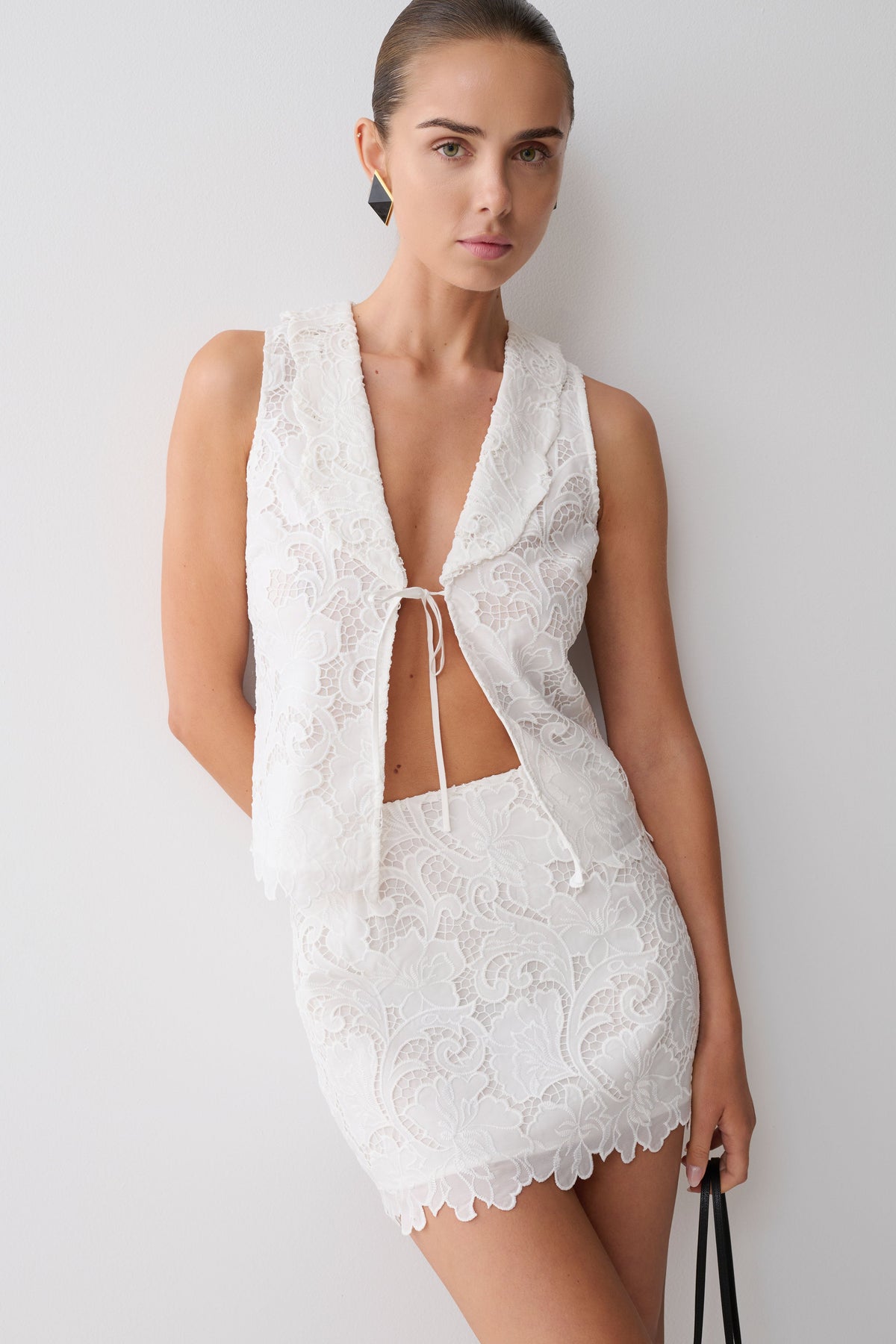 Woman wearing a white broderie tie top with matching mini skirt.