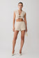 Woman wearing a beige tie front short sleeve top with matching shorts.