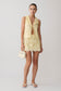 Woman wearing a yellow broderie tie top with matching mini skirt.