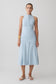 Woman wearing a light blue wrapped waist midi dress.