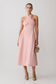 Woman wearing a pink croos over hallter maxi dress.