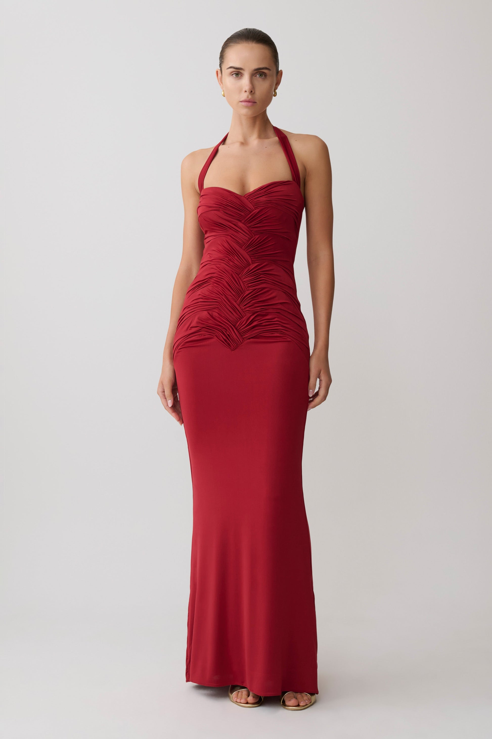 Woman wearing a gathered red halter neck maxi dress.