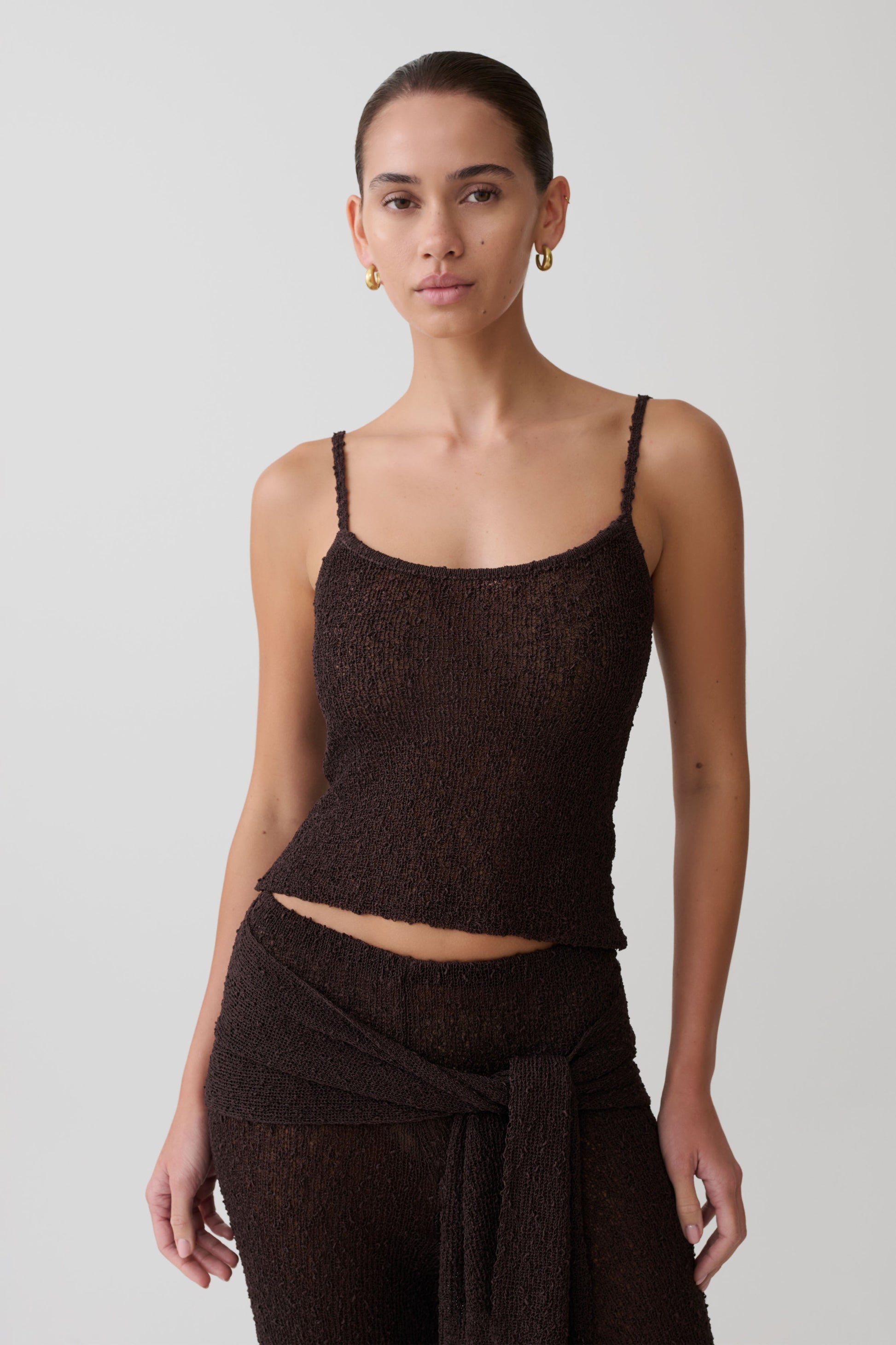 Woman wearing a brown boucle sleeveless top.