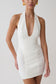 Woman wearing a white halter neck mini dress.
