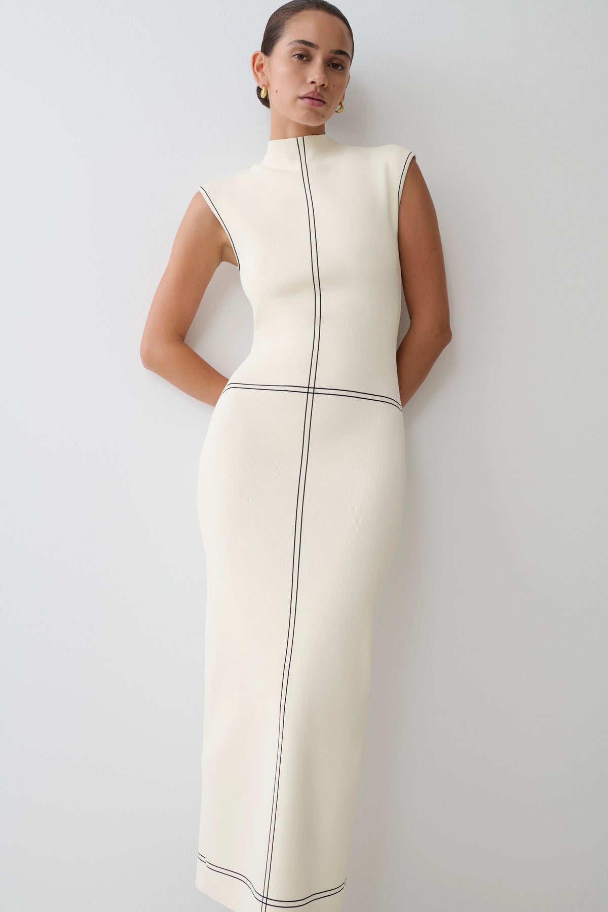 Woman wearing a white dress with black lined accents.