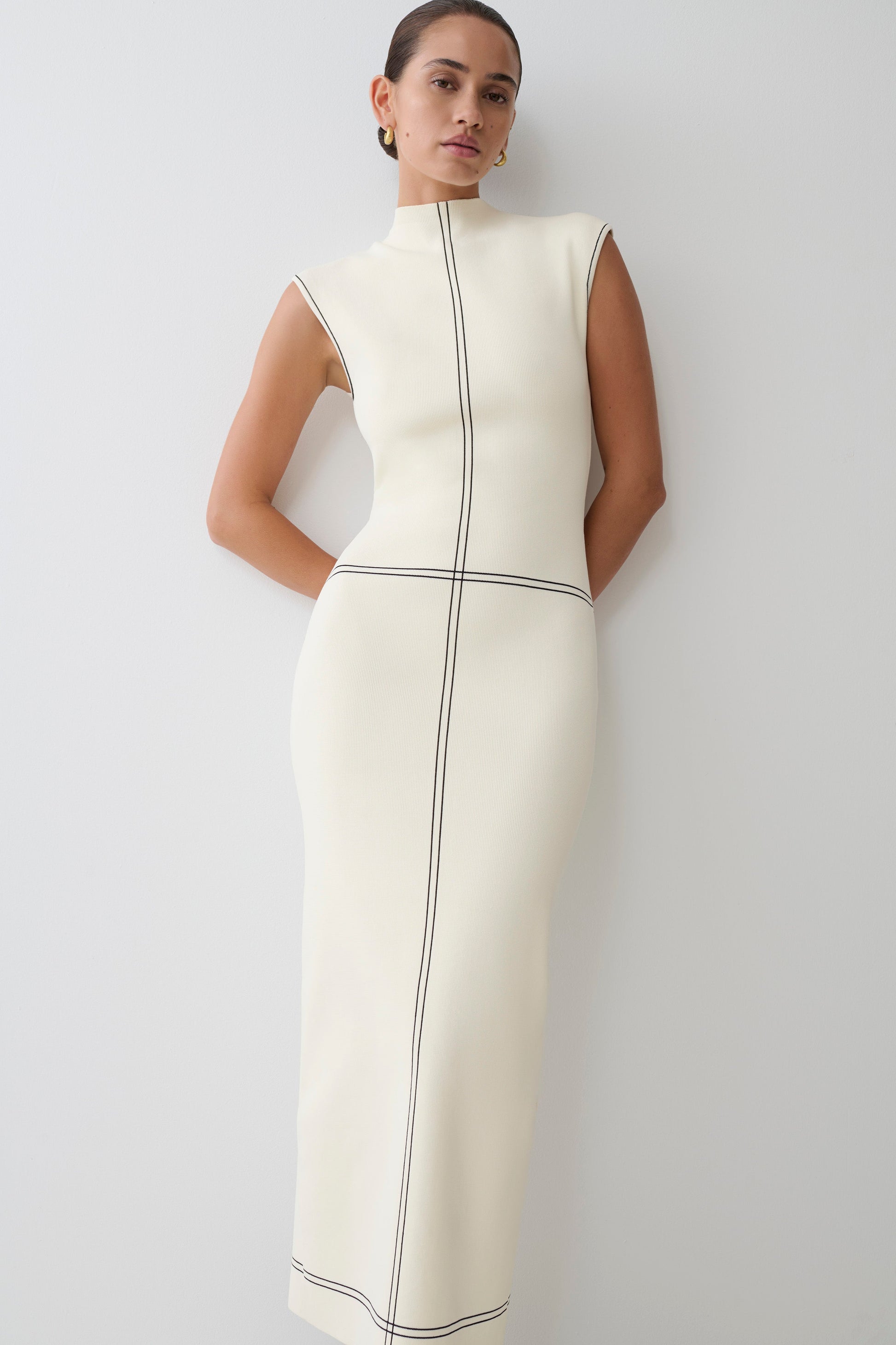 Woman wearing a white dress with black lined accents.