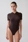 Woman wearing a brown bodysuit.