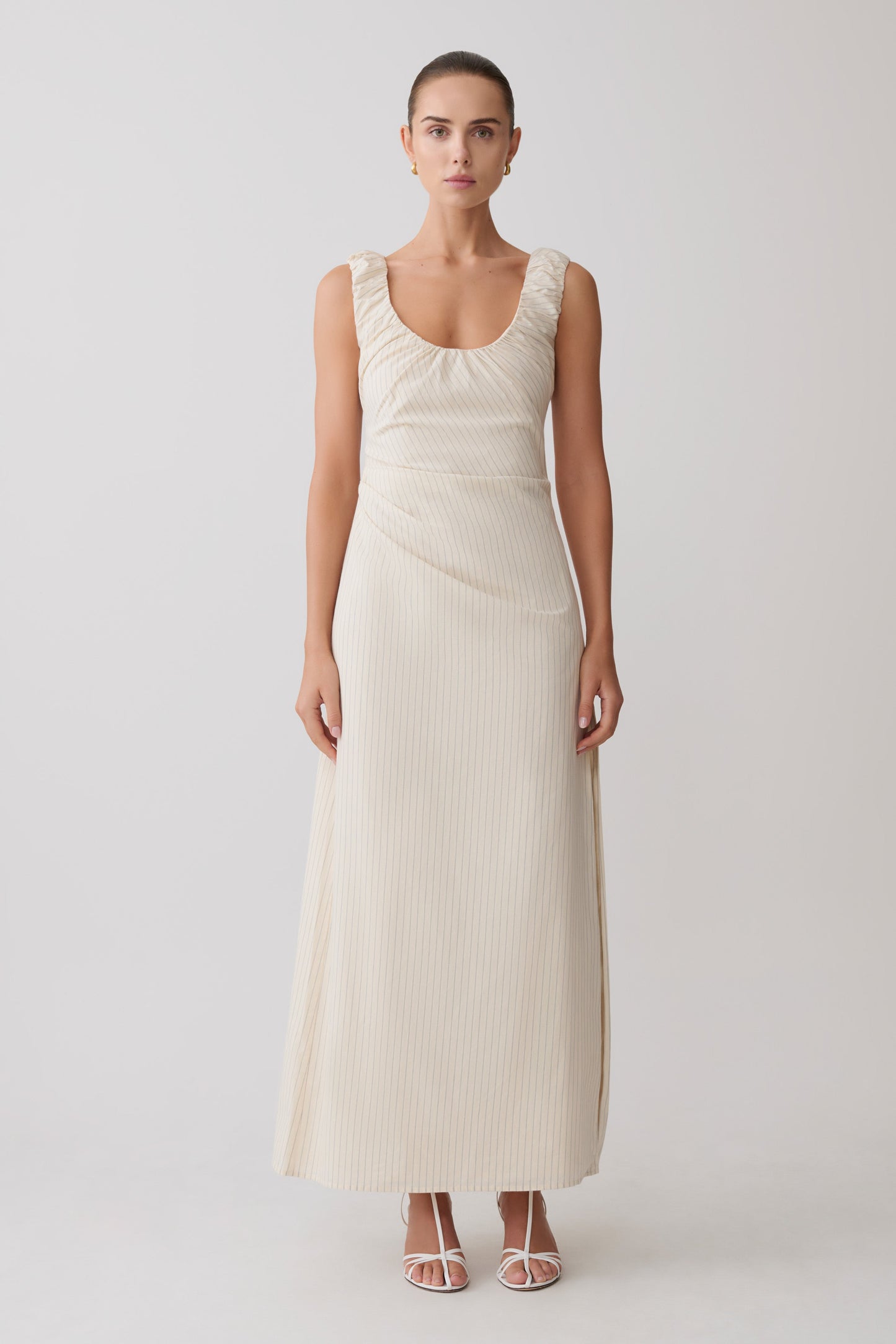 Woman wearing a cream-coloured striped maxi dress.