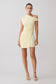Woman wearing a light yelllow one-shoulder mini dress.