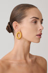 Woman wearing round gold studded earrings.