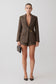 Woman wearing a brown blazer with gold hardware and matching shorts.