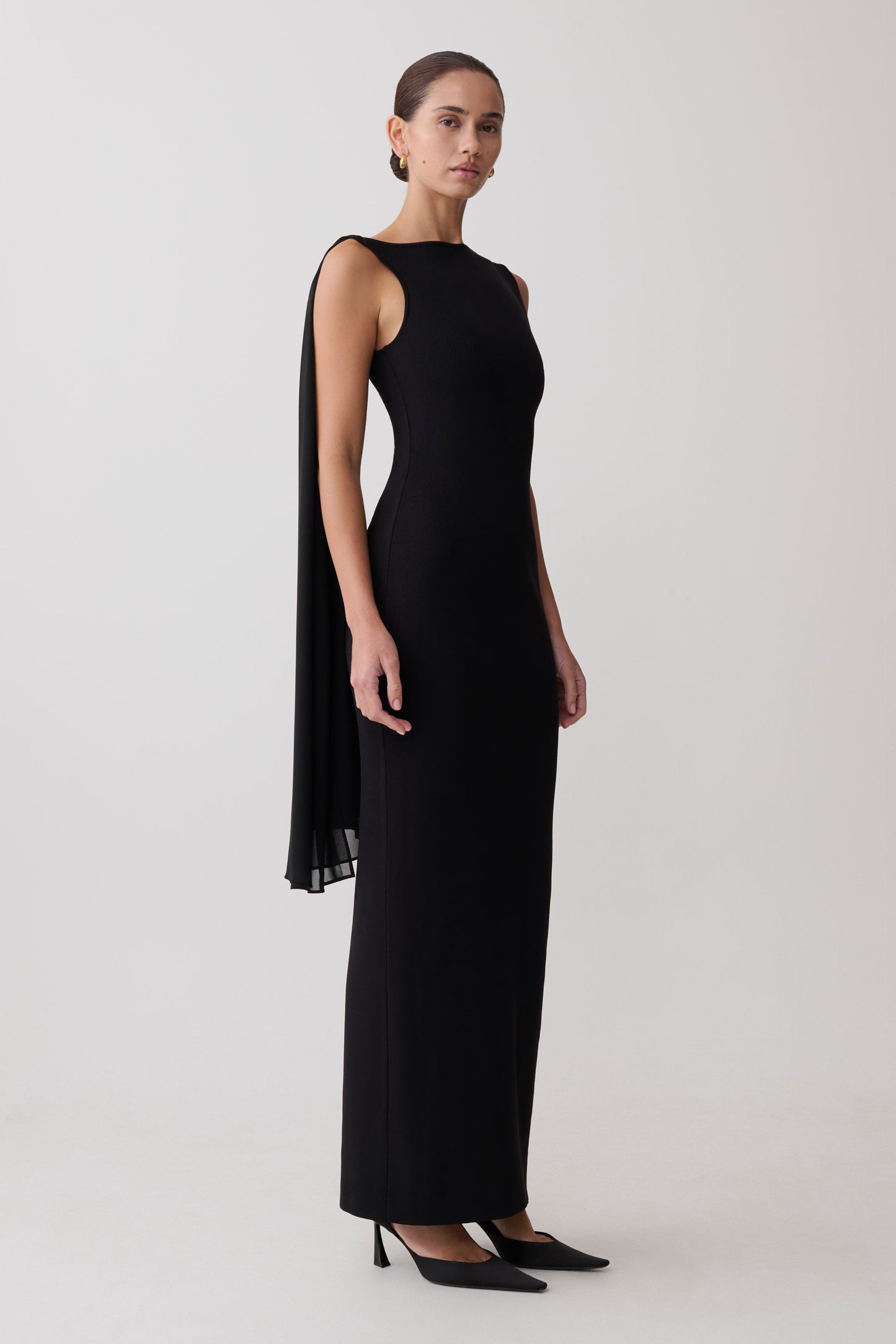 Woman wearing a black sleeveless dress with back scarf.