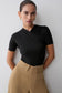 Woman wearing a black jumpsuit and brown pants.