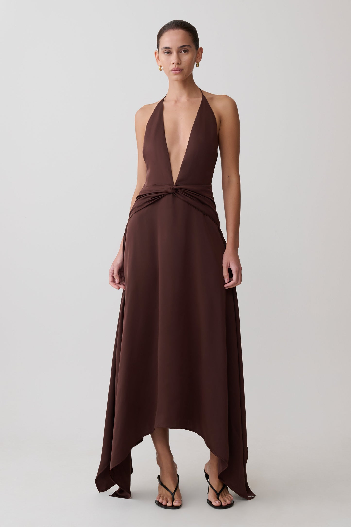 Woman wearing a brown halter neck dress on a white background