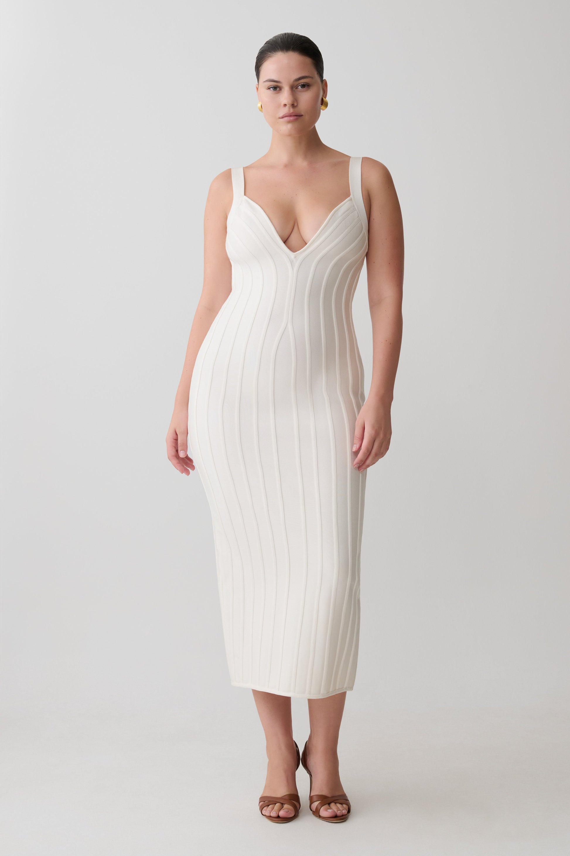Woman wearing a white ribbed dress on a plain background