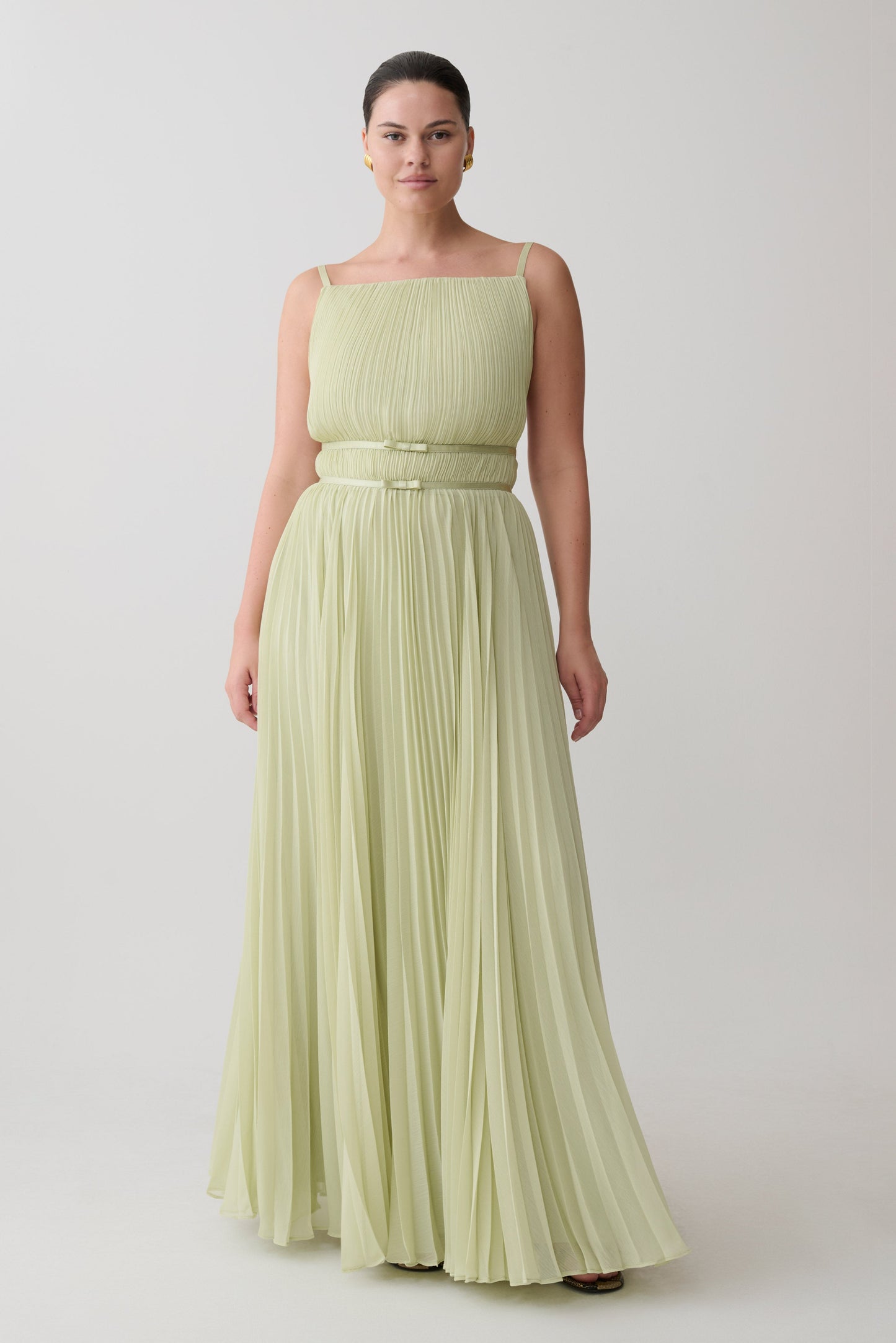 Woman wearing a light green strapless gown against a plain background