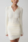 Woman wearing white ribbed dress with long sleeves.