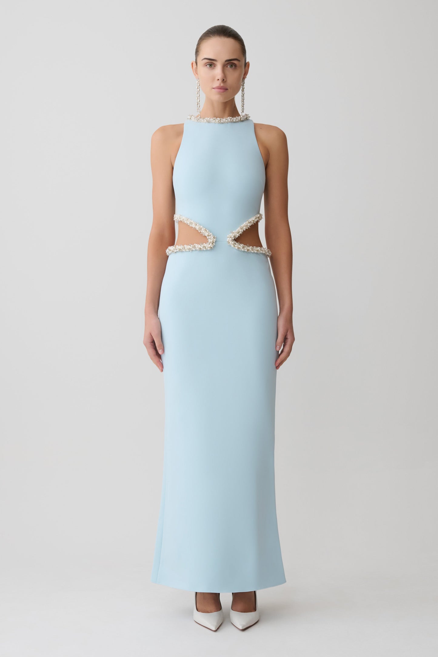 Woman wearing a light blue evening gown with lace details on a white background