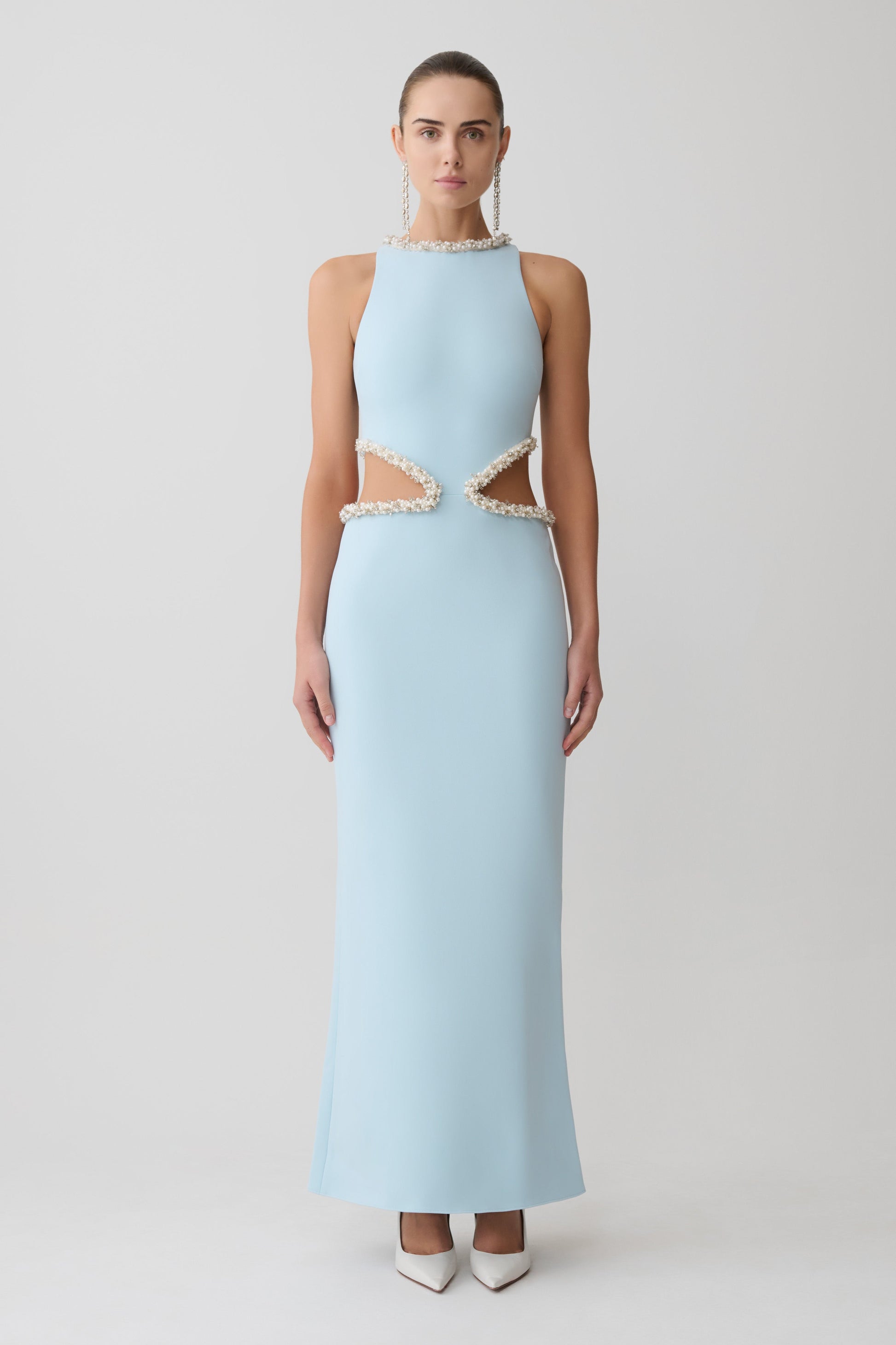 Woman wearing a light blue evening gown with lace details on a white background