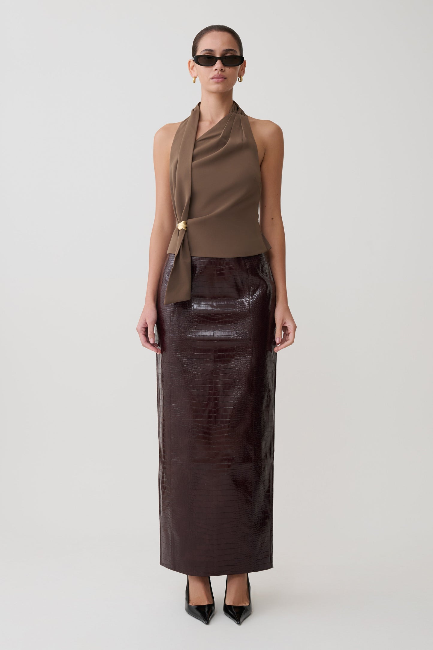 Woman wearing a brown top and dark brown leather skirt on a white background