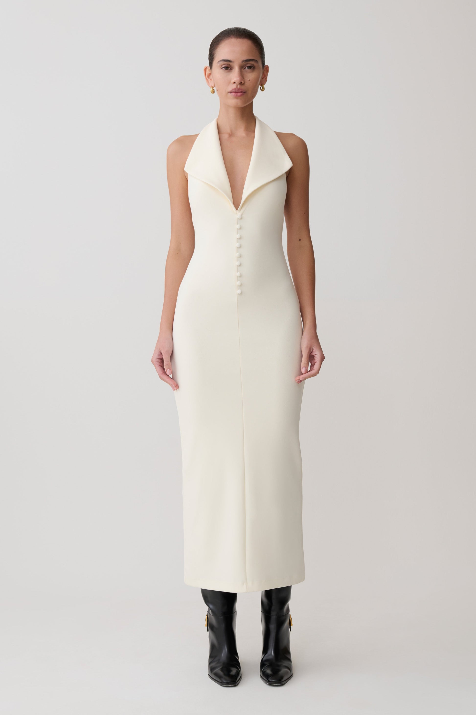 Woman wearing a white sleeveless dress with a deep neckline on a light gray background