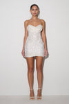 Woman wearing a strapless white sequin dress on a plain background