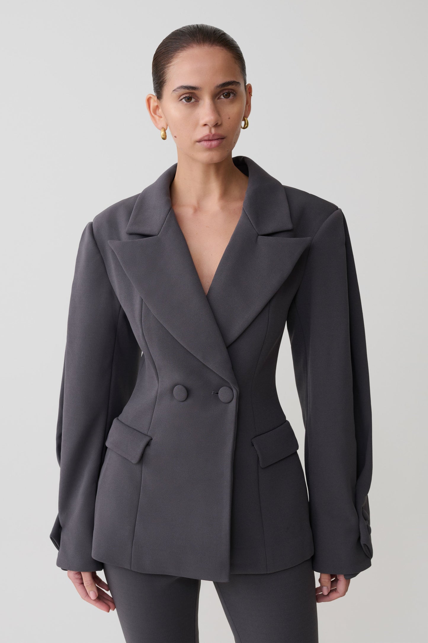 Woman wearing a gray blazer against a plain background
