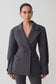 Woman wearing a gray blazer against a plain background
