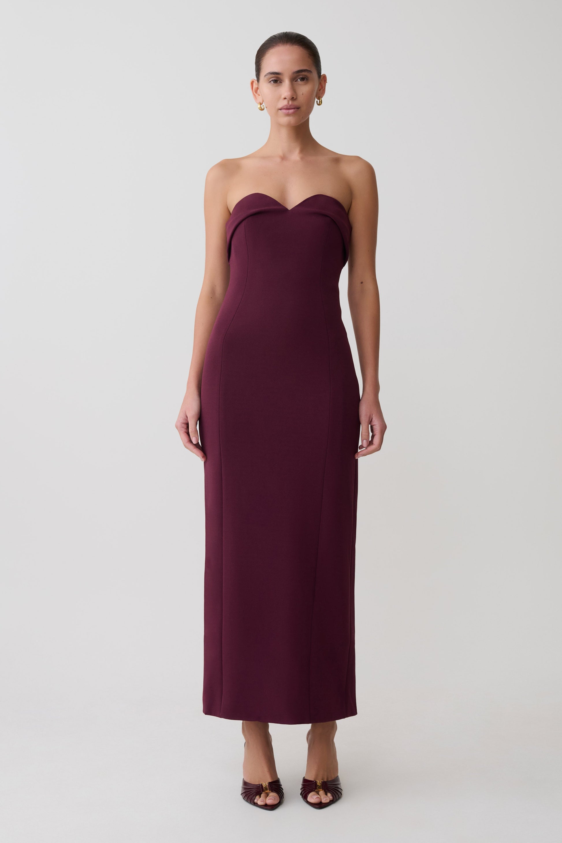 Woman wearing a strapless burgundy dress on a white background