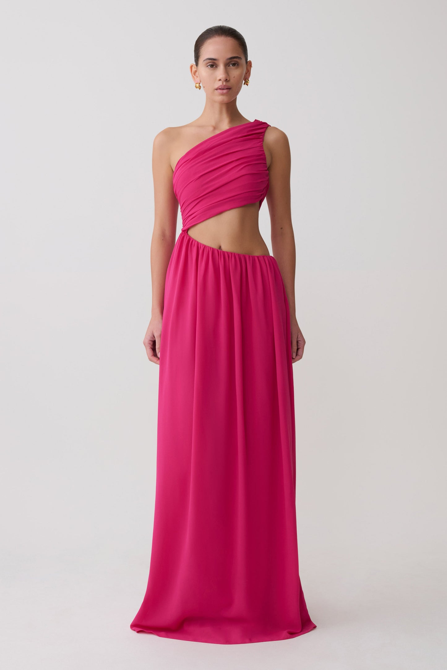 Woman wearing a pink one-shoulder dress with a cutout design on a white background