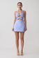 Woman wearing a light blue dress with a halter neck and bow detail on a white background