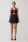 Woman wearing a black halter neck dress with cut-out design on a white background