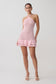 Woman wearing a pink crochet dress on a white background