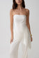 Woman wearing a silk blend strapless asymmetric top.