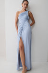 Woman wearing a light blue one-shoulder dress with a high slit on a white background