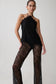 Model wearing a black lace top and pants on a plain background