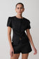 Woman wearing a black outfit with puffed sleeves on a plain background