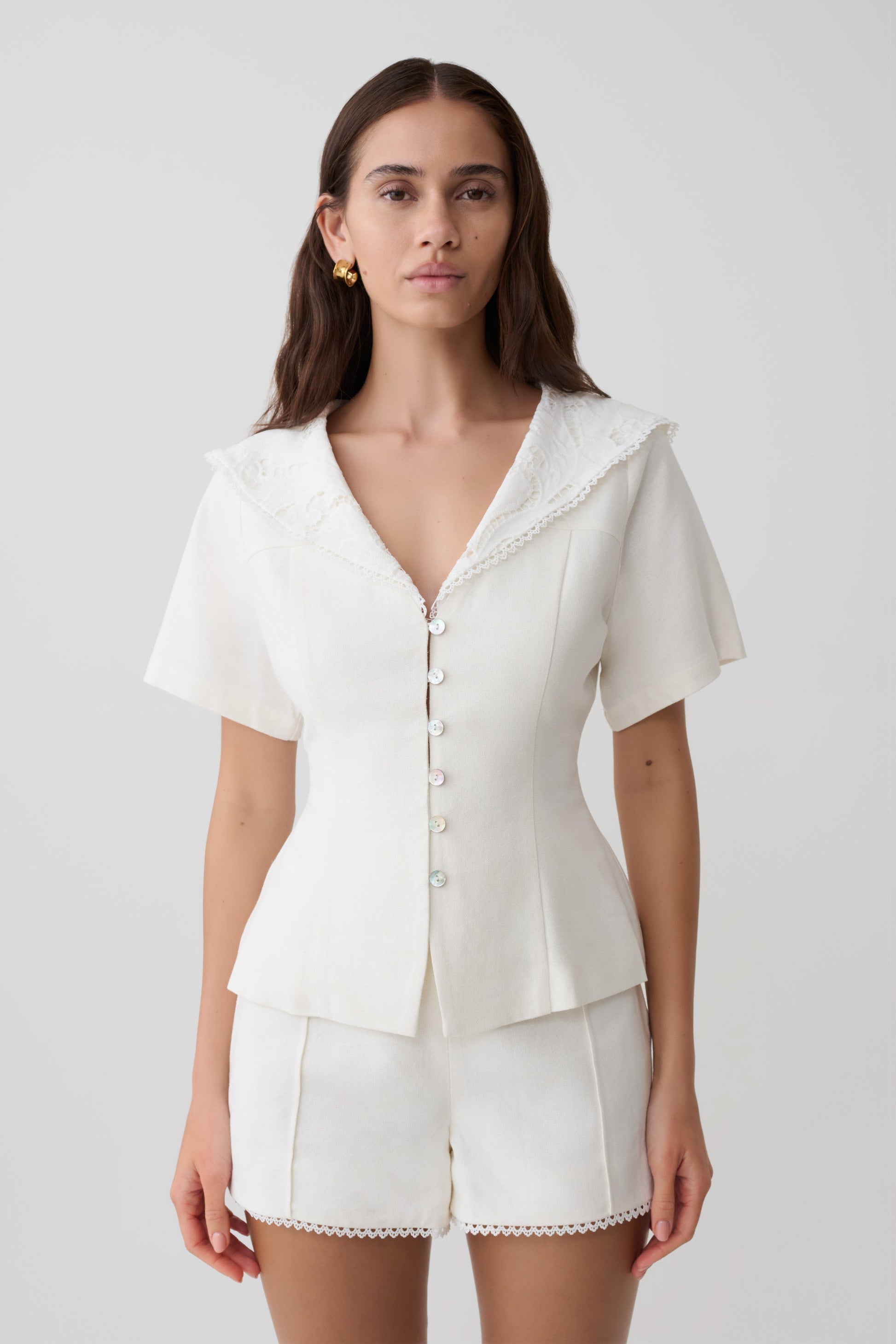 Woman wearing a white shortsleeve top with lace details.
