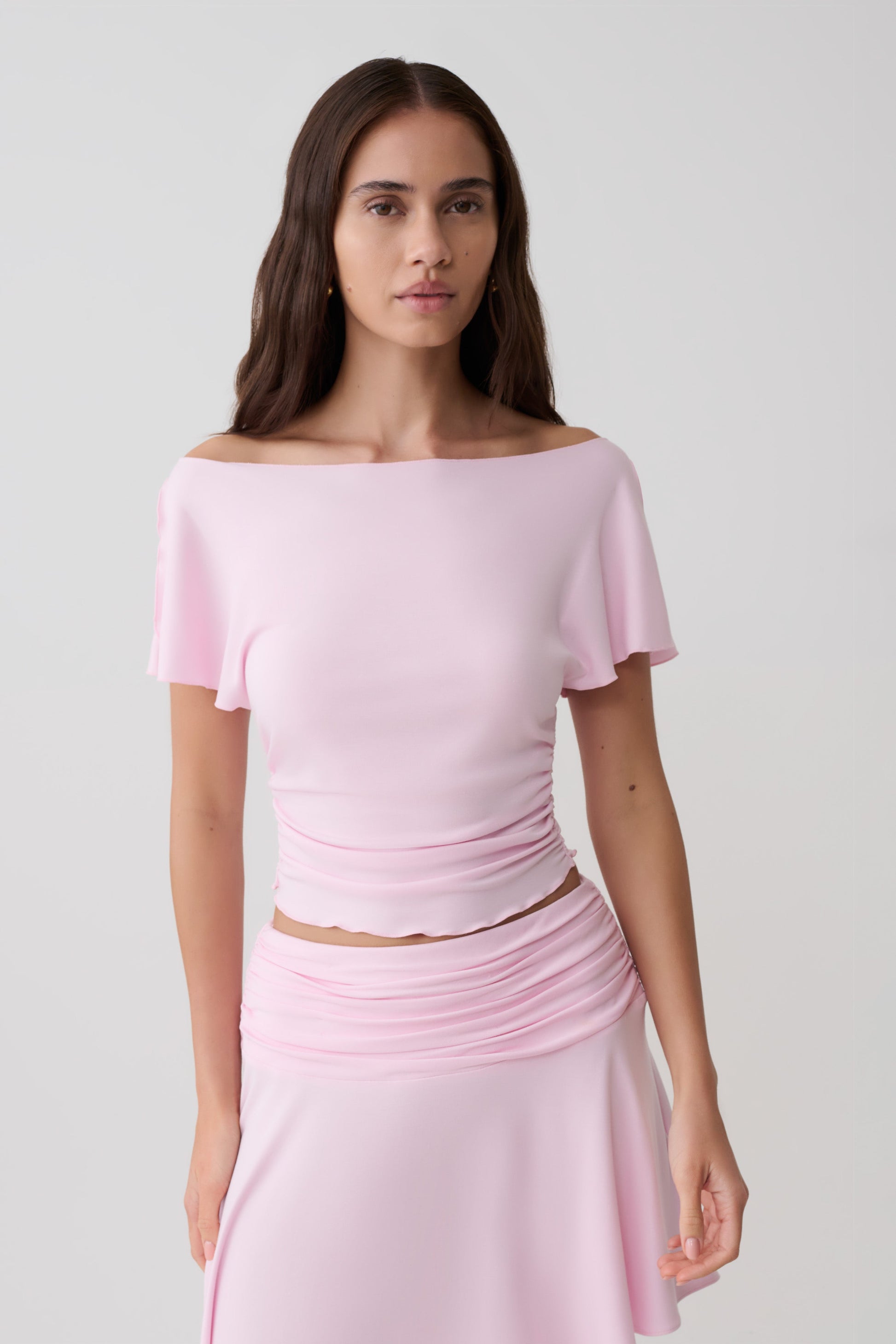 Woman wearing a pink short sleeve off-shoulder top.