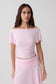 Woman wearing a pink short sleeve off-shoulder top.