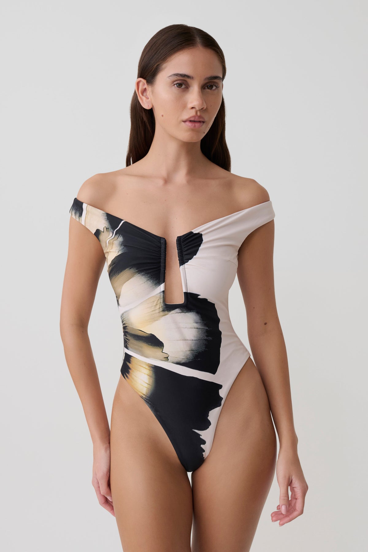Woman wearing a black and white floral off-shoulder swimsuit.