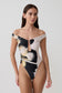 Woman wearing a black and white floral off-shoulder swimsuit.