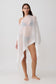Woman wearing a sheer white draped asymmetric top.