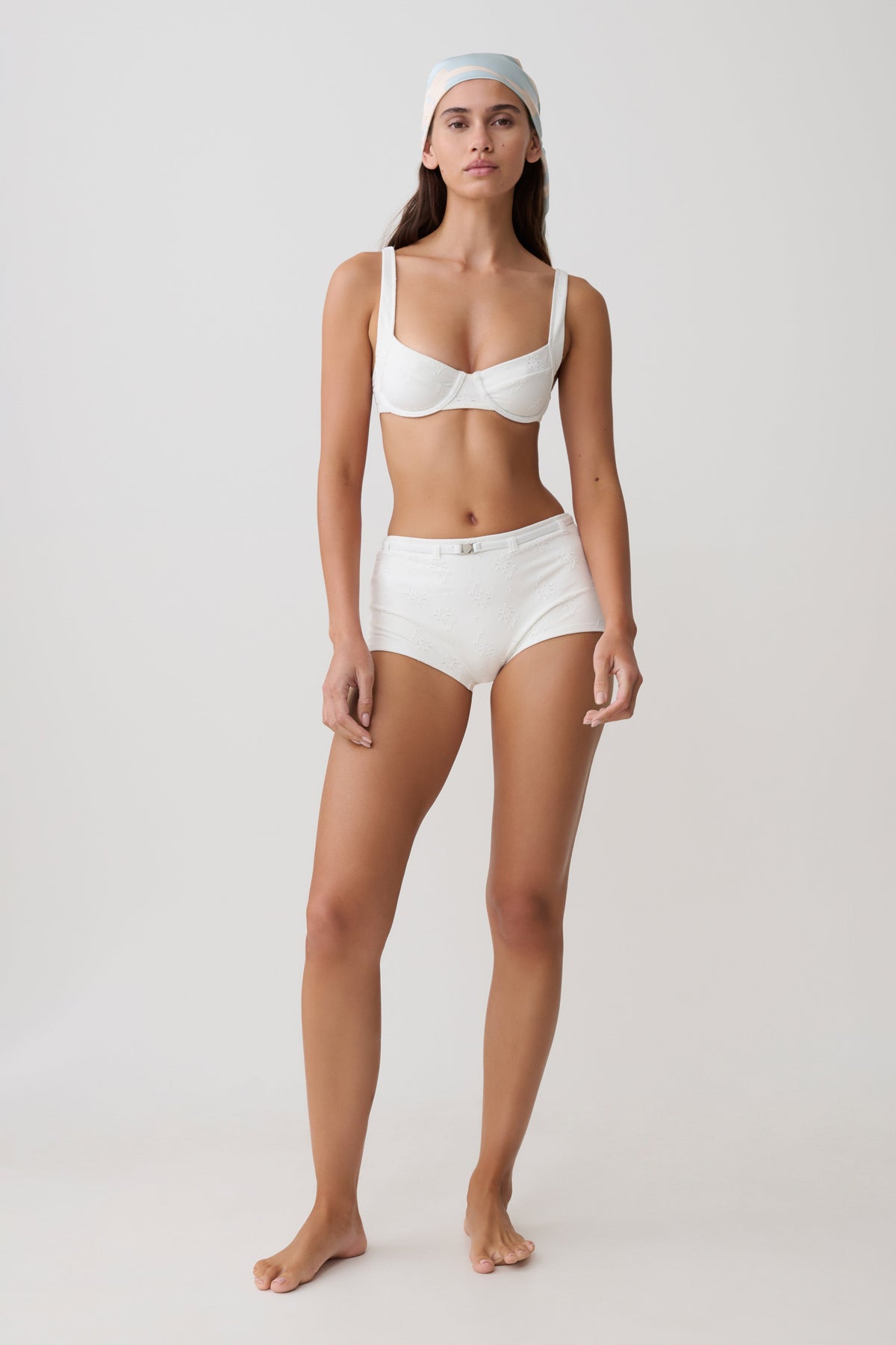 Woman wearing a white bikini set with micro shorts.