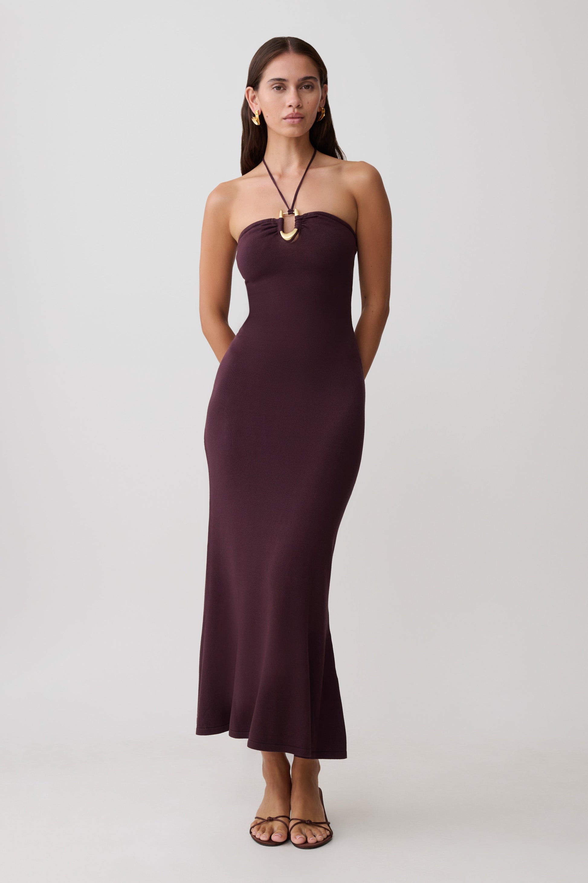 Woman wearing brown knit midi dress with neck hardware.