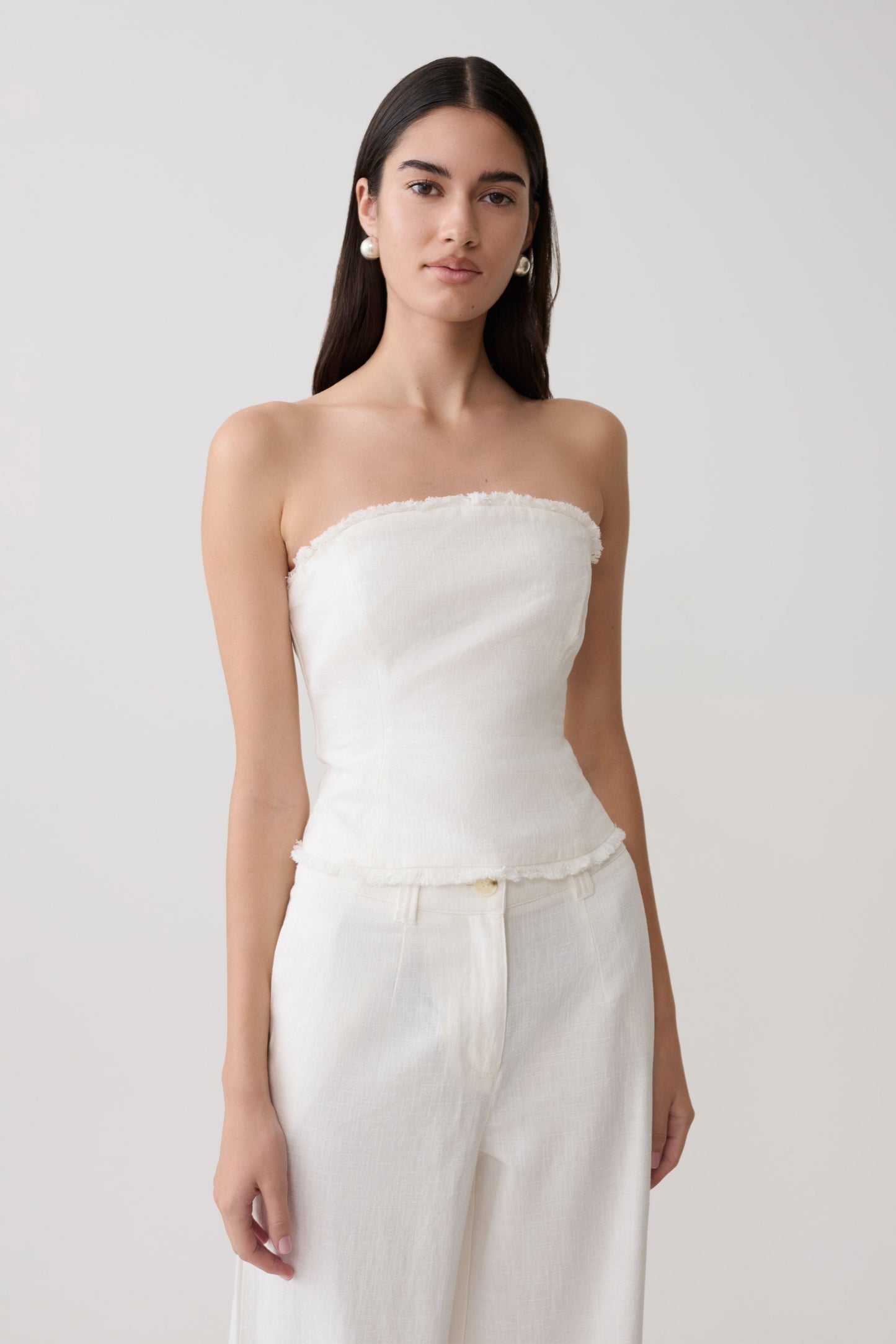 Woman wearing a white strapless tie back linen top.