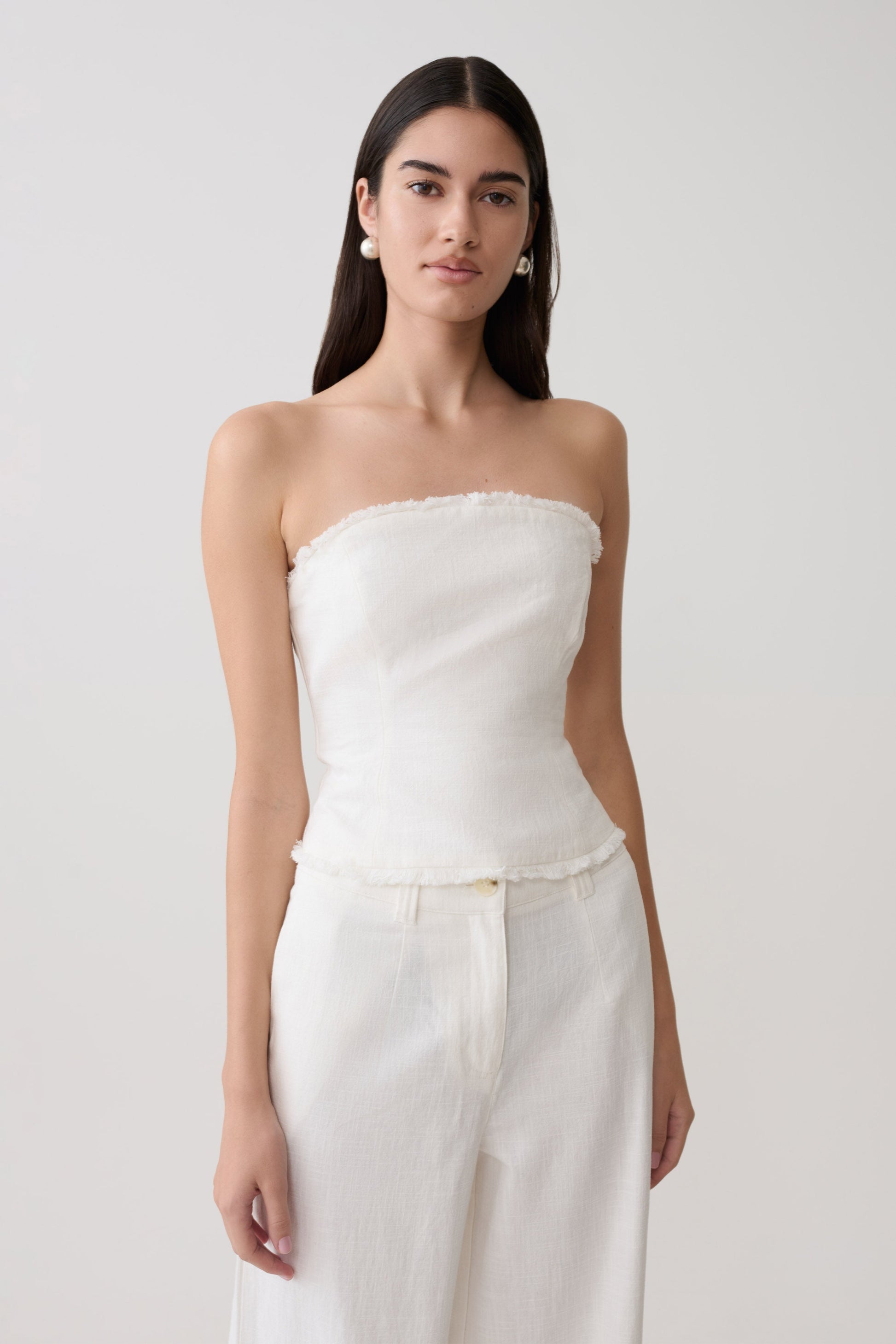 Woman wearing a white strapless tie back linen top.