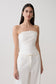 Woman wearing a white strapless tie back linen top.