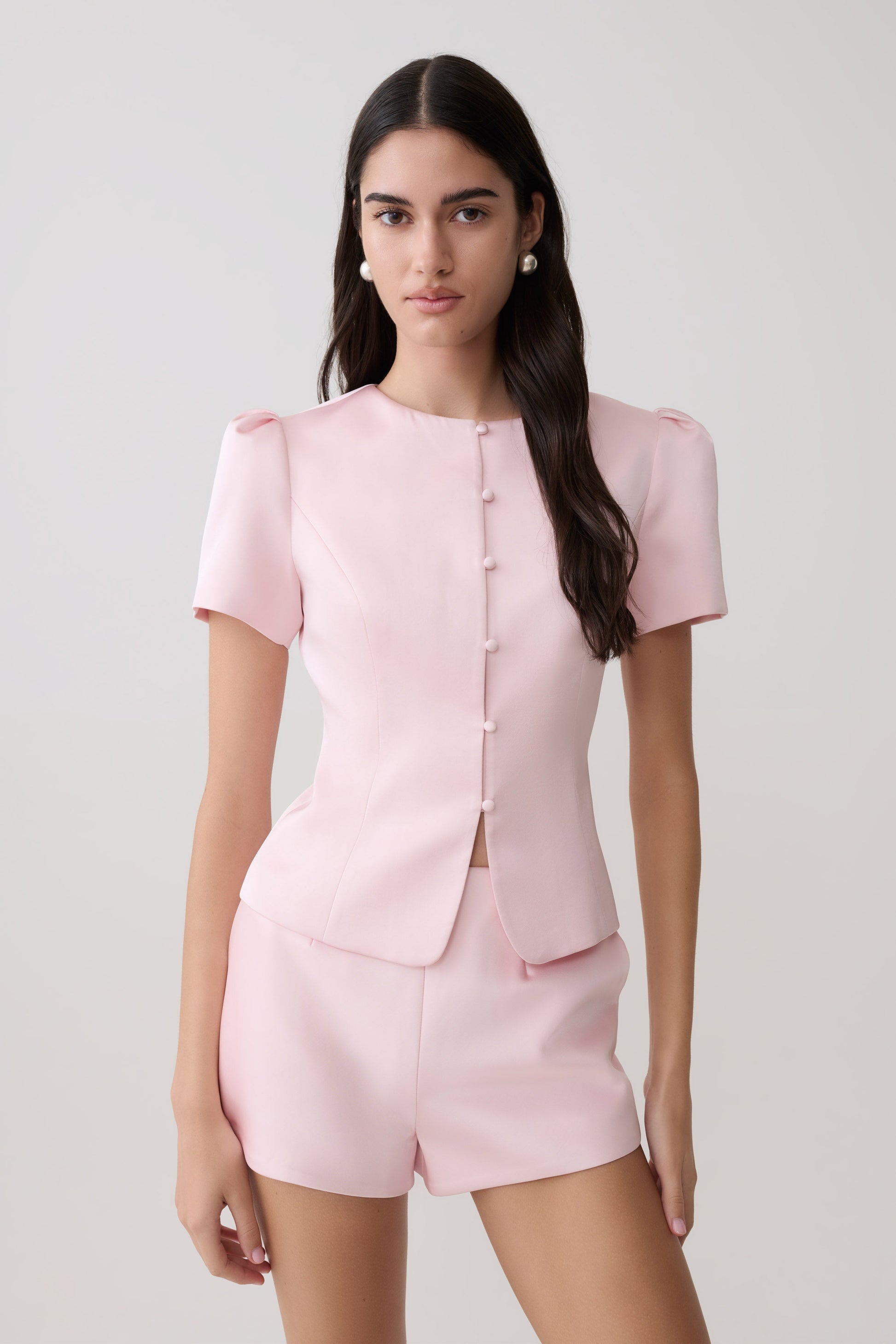 Woman wearing short sleeve pink satin top with matching shorts.